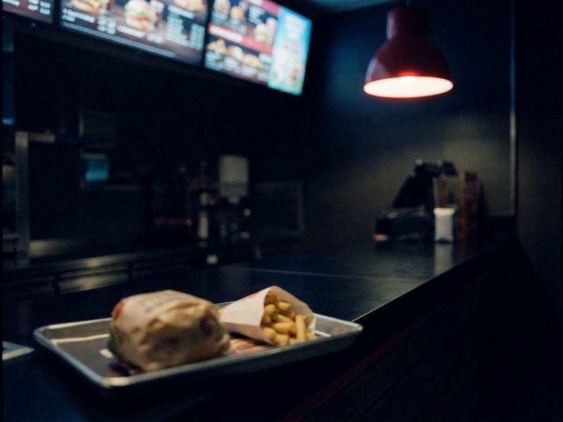A restaurant counter at night with a lit menu board